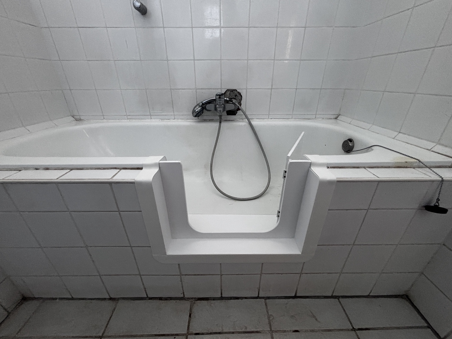 Nyitott ajtó – fehér csempés kád